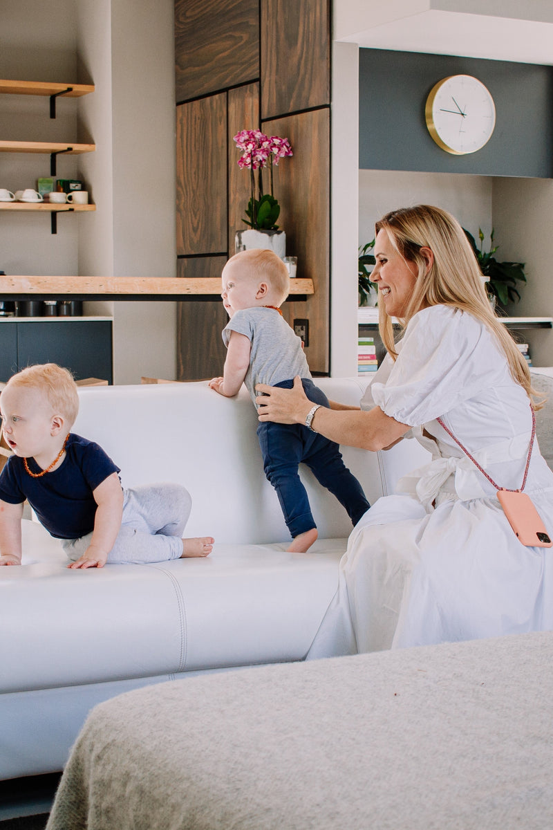 a woman playing with a baby on a white couch