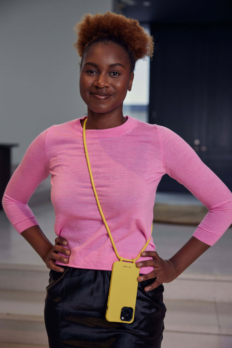 a woman in a pink shirt is holding a yellow cell phone